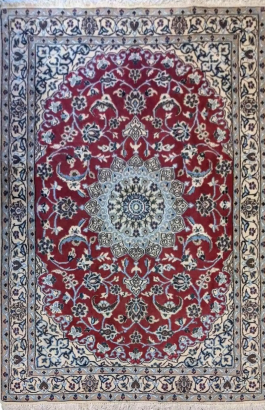 A traditional Persian Nain rug with a red primary color and intricate blue patterns, featuring floral and geometric designs.
