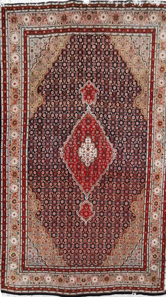 A traditional wool rug with a geometric 'Mahi' fish pattern in red and blue colors, and a border in a lighter shade.