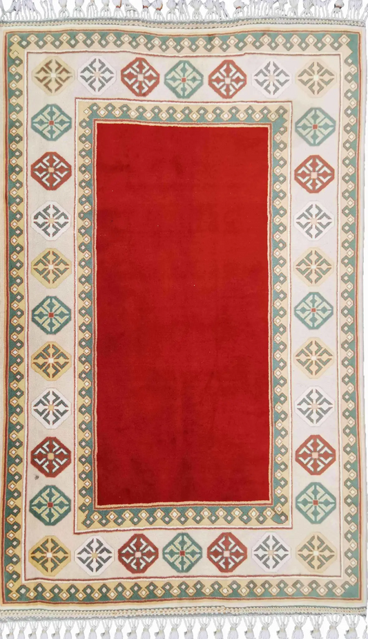 A rectangular Tunisian tribal wool rug with a red center and beige border, featuring geometric and floral patterns.