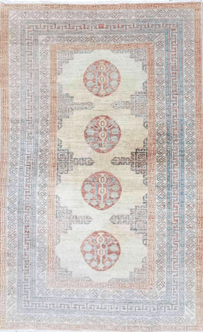 A Kazak wool rug featuring a geometric pattern with bold angles, primarily beige with red accents, and decorative elements along the borders.