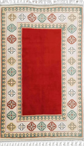 A rectangular Tunisian tribal wool rug with a red center and beige border, featuring geometric and floral patterns.