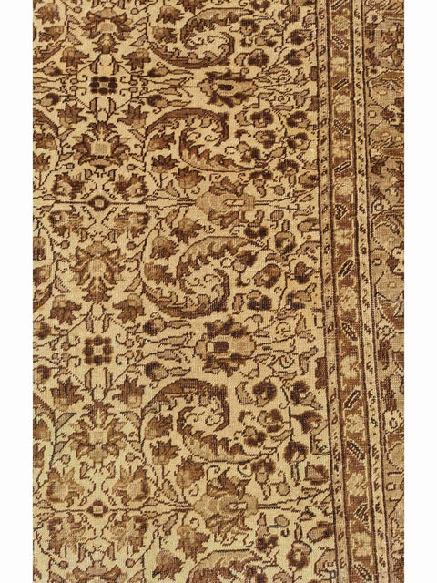 A beige and brown colored wool rug with a traditional geometric pattern.