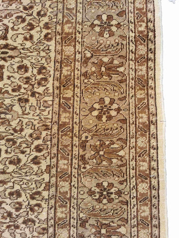 A beige and brown colored wool rug with a traditional geometric pattern.