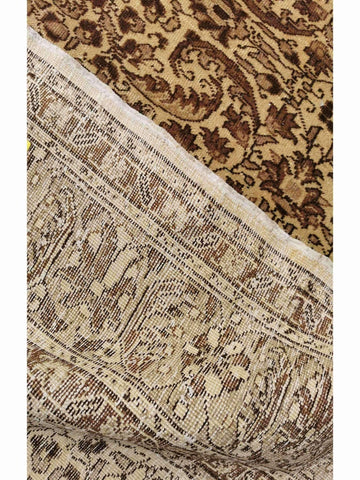 A beige and brown colored wool rug with a traditional geometric pattern.