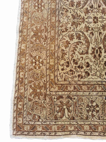 A beige and brown colored wool rug with a traditional geometric pattern.
