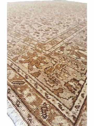 A beige and brown colored wool rug with a traditional geometric pattern.