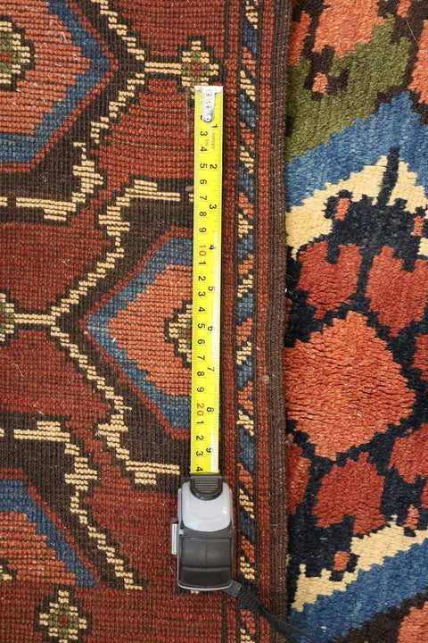 A geometric patterned Afghan Tribal Wool Rug in beige, red, and other colors.