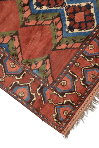 A geometric patterned Afghan Tribal Wool Rug in beige, red, and other colors.