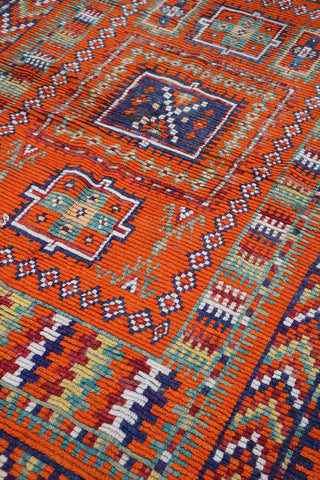 A vibrant orange and multicolored Berber tribal wool rug