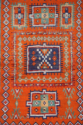 A vibrant orange and multicolored Berber tribal wool rug
