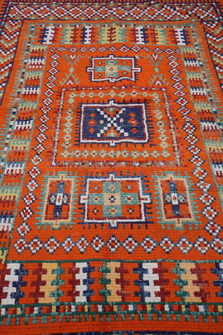 A vibrant orange and multicolored Berber tribal wool rug