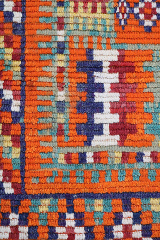 A vibrant orange and multicolored Berber tribal wool rug
