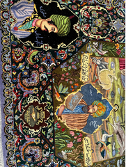 Decorative rug with intricate patterns and figures, featuring a person in a green headscarf and another in a blue outfit.